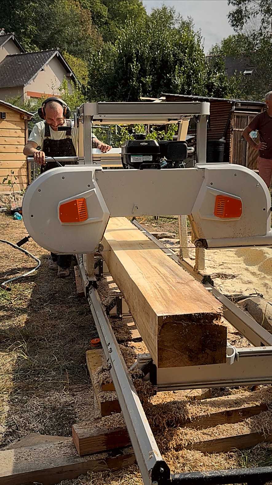 Scieur derrière sa scie mobile à ruban en train de débiter une bille