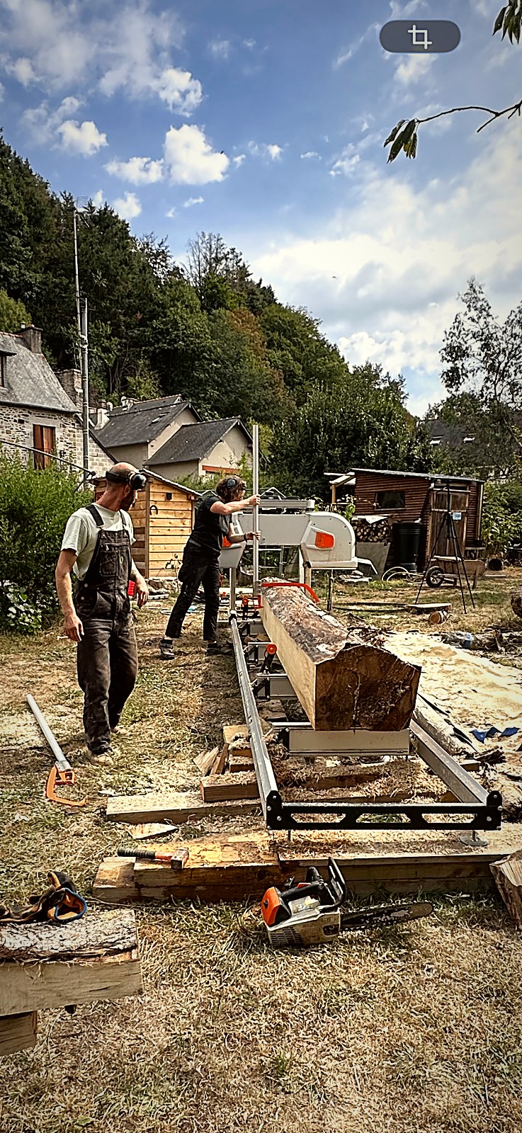 Chantier de sciage mobile installé dans un jardin breton, grume sur le banc